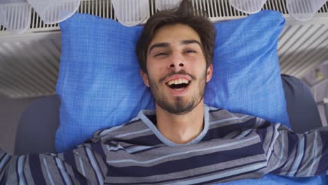 Young-man-waking-up-and-yawning-smiling.-Happy-morning.